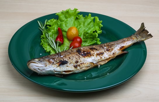 Grilled trout on the plate and wooden background photo