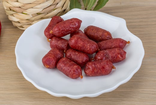 Mini salami on the plate and wooden background photo