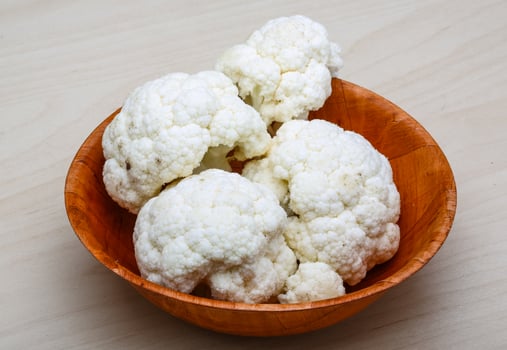 Cauliflower in a bowl on wooden background photo