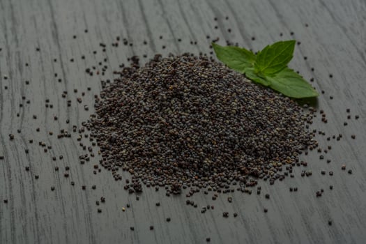 Poppy seeds on wooden background photo