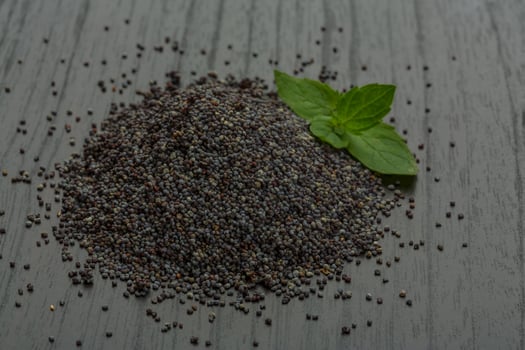 Poppy seeds on wooden background photo