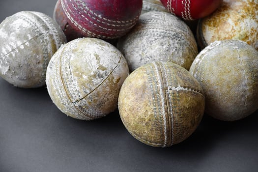 Old training cricket sport equipments on dark floor, leather ball, wickets, helmet and wooden bat, soft and selective focus, traditional cricket sport lovers around the world concept. photo