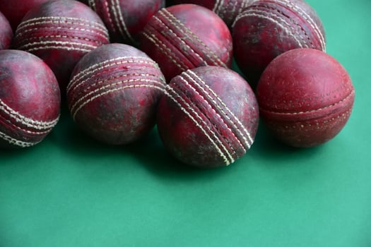 Old training cricket sport equipments on dark floor, leather ball, wickets, helmet and wooden bat, soft and selective focus, traditional cricket sport lovers around the world concept. photo