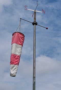White and red windsock isolated on blue sky background. Check the wind blow direction concept photo