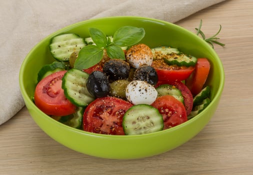 Salad with mozzarella and tomatoes in a bowl on wooden background photo