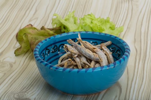 Dries anchovy in a bowl on wooden background photo