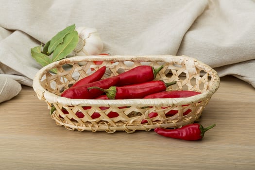 Chili peppers in a basket on wooden background photo