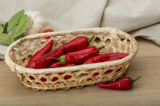 Chili peppers in a basket on wooden background photo