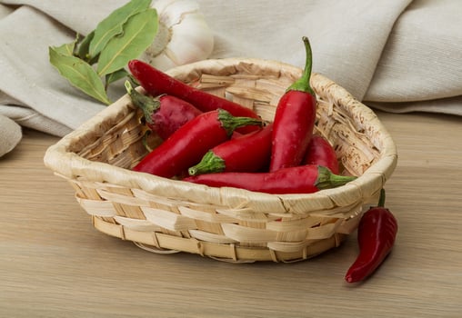 Chili peppers in a basket on wooden background photo