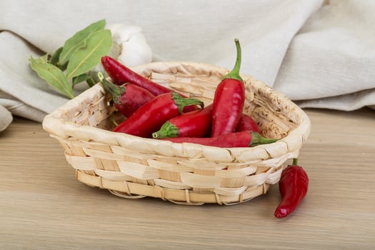 Chili peppers in a basket on wooden background photo