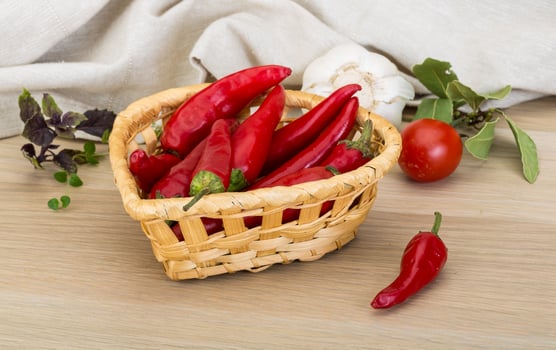 Chili peppers in a basket on wooden background photo