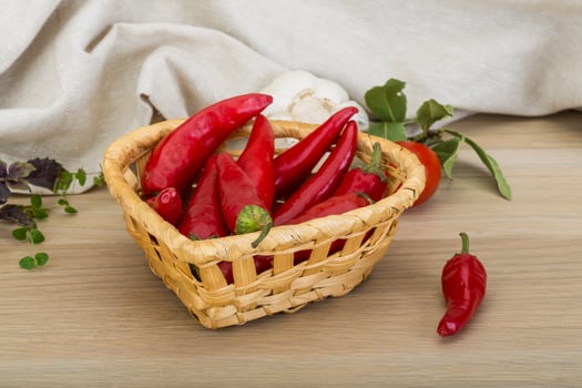 Chili peppers in a basket on wooden background photo