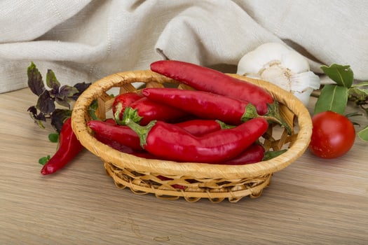 Chili peppers in a basket on wooden background photo