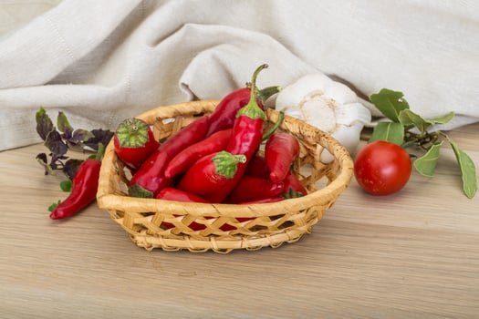 Chili peppers in a basket on wooden background photo