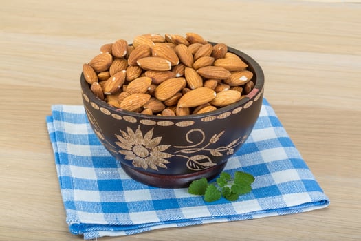 Almond in the bowl in a bowl on wooden background photo