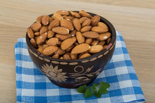 Almond in the bowl in a bowl on wooden background photo