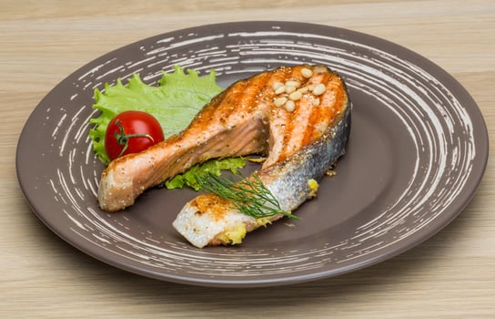 Grilled salmon steak on the plate and wooden background photo