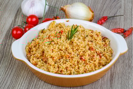 Couscous in a bowl on wooden background photo