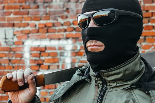 Commando in a mask and glasses with a machete in his hand against a brick wall photo