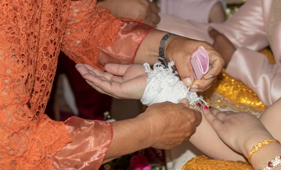 The elderly hand tied the thread to the bride. photo