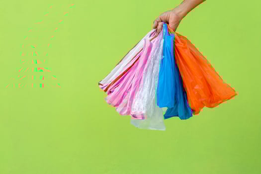 Many plastic bags in the hand against the green wall. photo