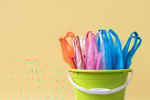 Plastic bags are packed in a green container with a yellow concrete wall. photo