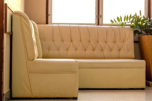 Old cream-colored sofa in the corner of the room with window light. photo