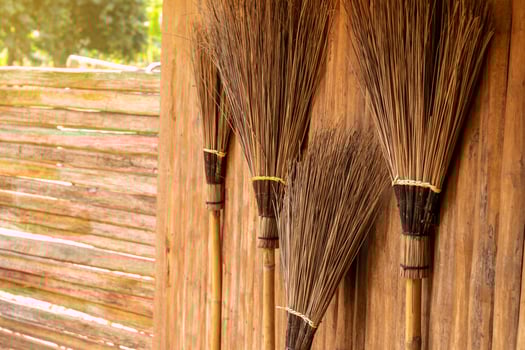 The broom is leaning against a wooden wall. photo