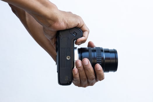 Isolated close-up of the hands and fingers of a Thai man holding an old black DSLR film camera. photo