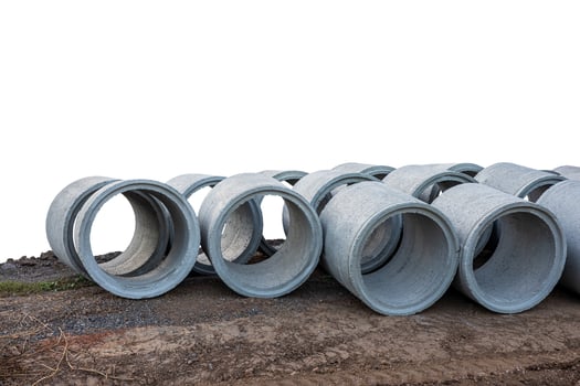 Low view isolates, large concrete pipes lined up on the ground beside roads. photo