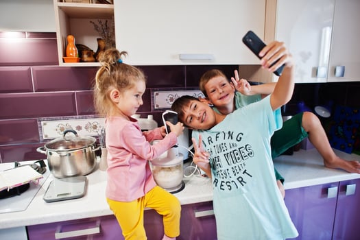 Kids cooking at kitchen, happy children's moments. Making selfie on phone. photo