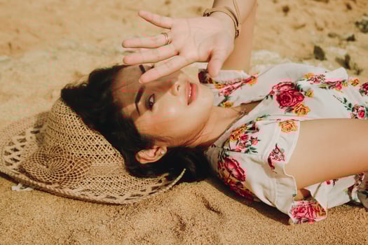 A young beautiful Asian woman dazzled by the light while lying on the beach sand photo