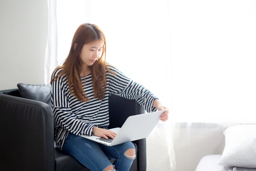 Beautiful of portrait young asian woman using laptop computer  for leisure on chair at living room, girl working online with notebook freelance, communication business concept. photo