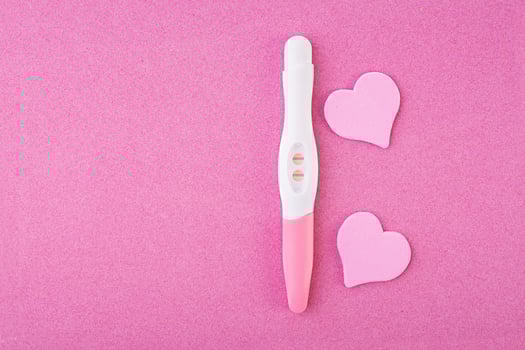 Positive pregnancy test with hearts isolated on pink background photo