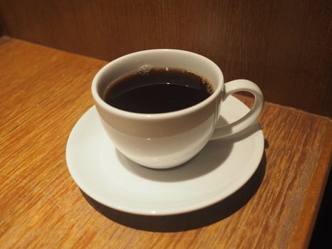 smoke on Black coffee in a white cup placed on a wooden table photo