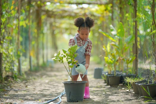 Litte Afro Kid Farmer Girl In garden watering plants and Harvest vegetables. photo