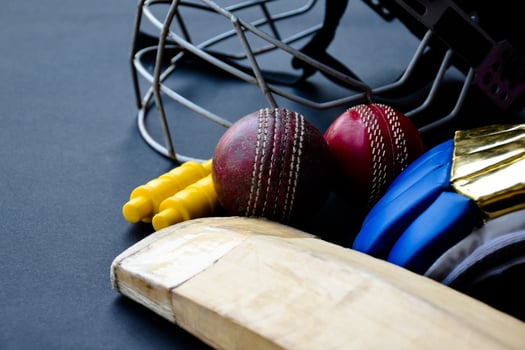 Old training cricket sport equipments on dark floor, leather ball, wickets, helmet and wooden bat, soft and selective focus, traditional cricket sport lovers around the world concept. photo