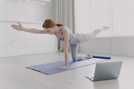 Young woman enjoying yoga by video lessons. Morning exercise and sport routine concept. photo