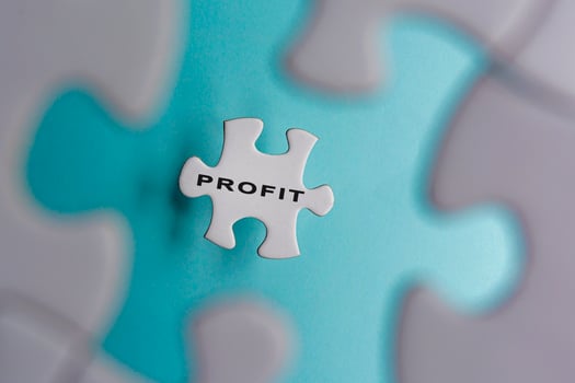 Profit word on puzzle pieces isolated on blue background. Business concept. photo