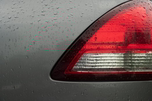 Close up beside of tail light red and white color. Car gray color. On the boy with drop of rain. photo
