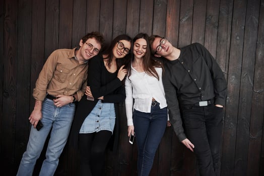 Relaxed and happy. Youth stands against black wooden wall. Group of friends spending time together photo