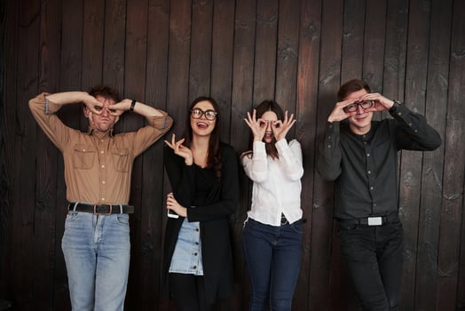 That's what you do when you bored. Youth stands against black wooden wall. Group of friends spending time together photo