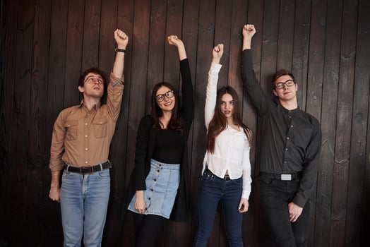Celebrating succeess. Friends put their hands up gainst black wooden wall photo