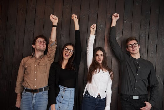 Stylish youth. Celebrating succeess. Friends put their hands up against black wooden wall photo