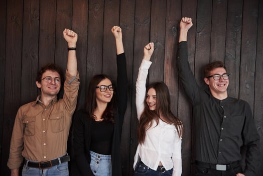 Bonding of people. Celebrating succeess. Friends put their hands up against black wooden wall photo
