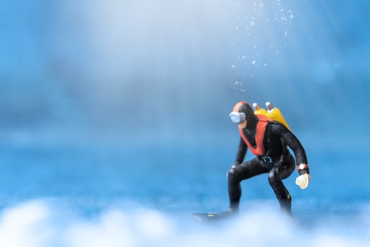 Miniature people Scuba Diver standing underwater with blue background photo