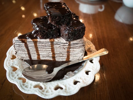Chocolate cake with brownie and vanilla on a white plate on a wooden table at a coffee shop.Selective focus photo