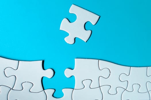 Piece of jigsaw puzzle on blue paper. Directly above. Copy space. photo