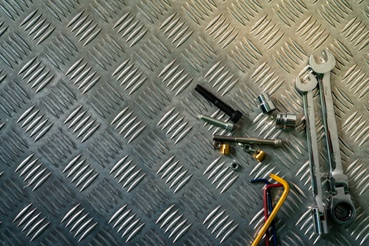 Top view of tools on industrial metal checker plate. Metal checkerplate for anti skid. Nut, bolts, and hex key on metal sheet floor. Silver bump ground with art pattern. Silver texture background. photo
