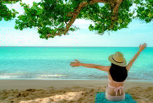Back view of happy young Asian woman in pink swimsuit and straw hat relax and enjoy holiday at tropical sand beach under the tree. Girl in summer vacation fashion. Beauty sexy model. Summer vibes. photo